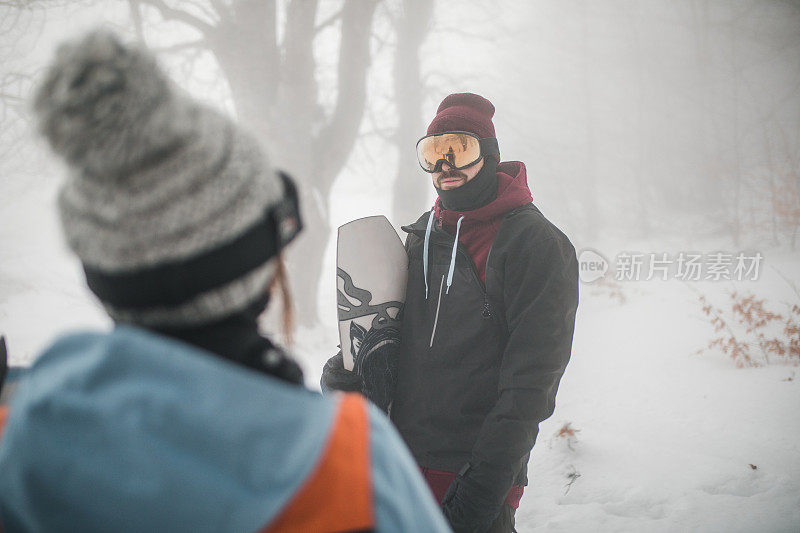 男女滑雪者在滑雪前穿着冬装在山上随意聊天