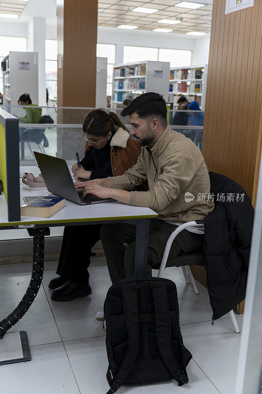 一所大学的两个学生在图书馆学习。