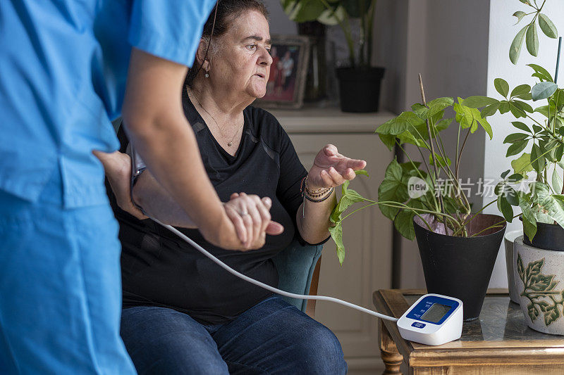 男护士在家中为一位老年妇女测量血压