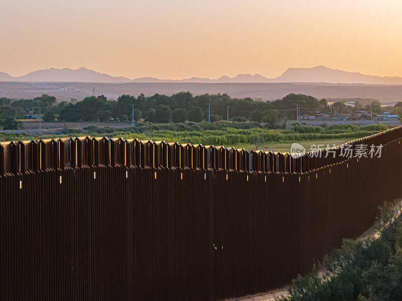 日落在美国和墨西哥之间的美国边境墙上