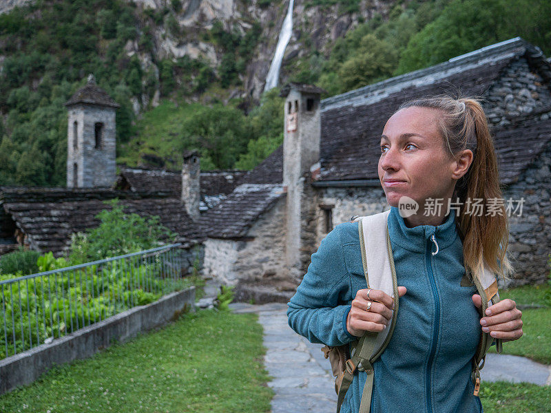 女人在大自然中漫步，她在有瀑布的石头村庄漫步