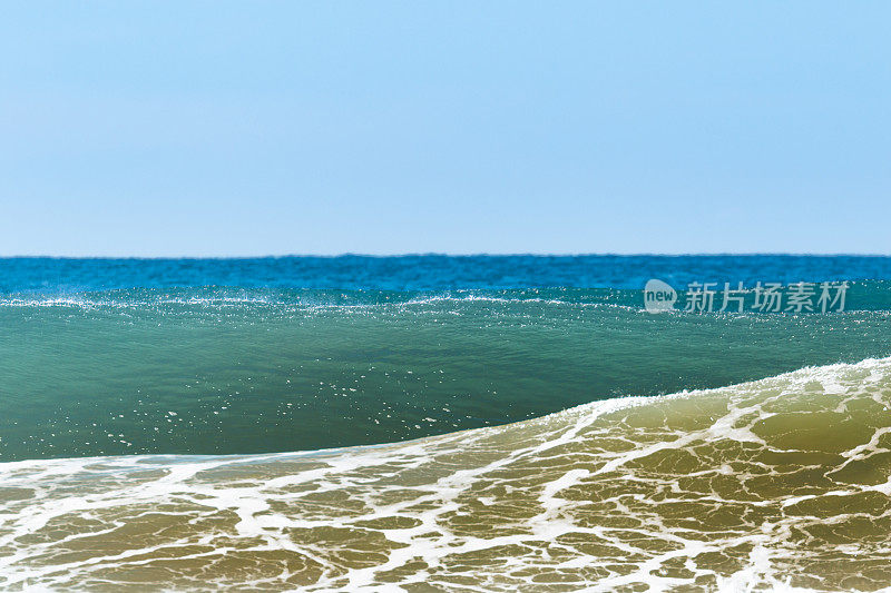 一个波浪在海岸附近破浪而出。