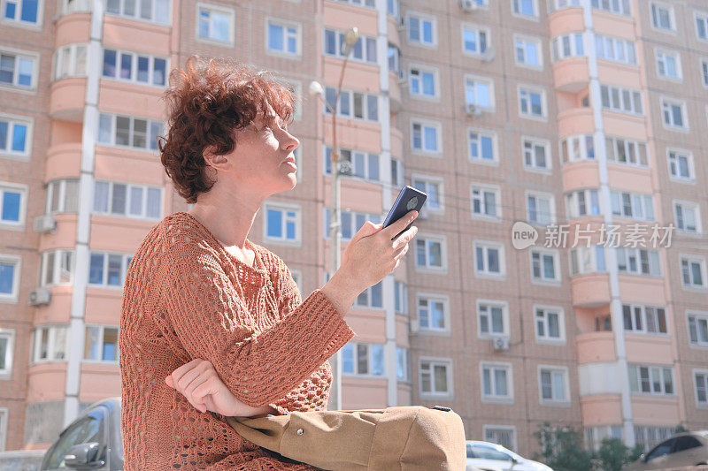 成熟的女人正在寻找城市里的地址。她正在用智能手机上的地图