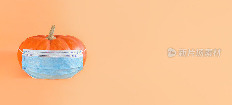 橙色南瓜在蓝色医疗面具米色的背景，宽横幅与复制空间。