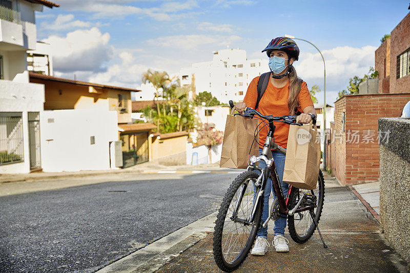 西班牙裔年轻女子寻找地址，而骑自行车为家庭送货服务