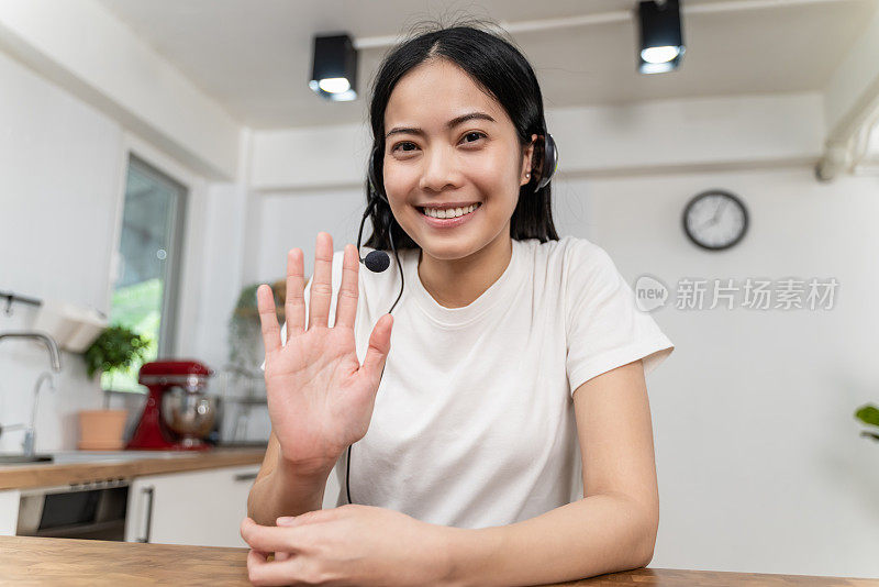 有吸引力的年轻亚洲女人视频通话，挥手和看着相机。