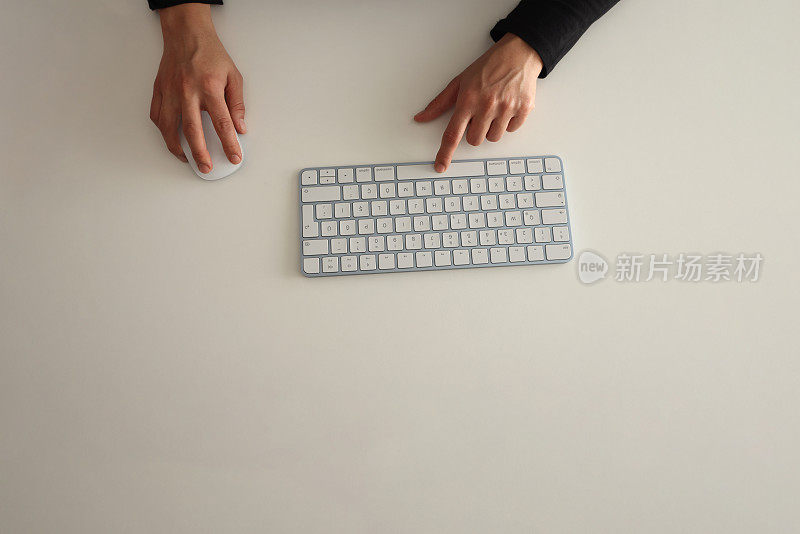 女性的手在白色的电脑键盘上打字