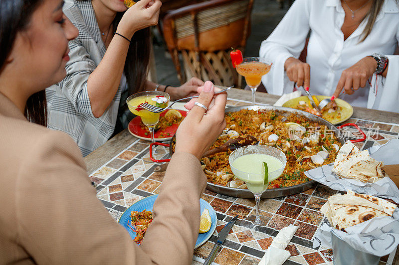 年轻女性在户外餐厅的餐桌上，午餐吃海鲜饭