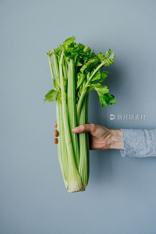 女人手握新鲜芹菜的特写照片