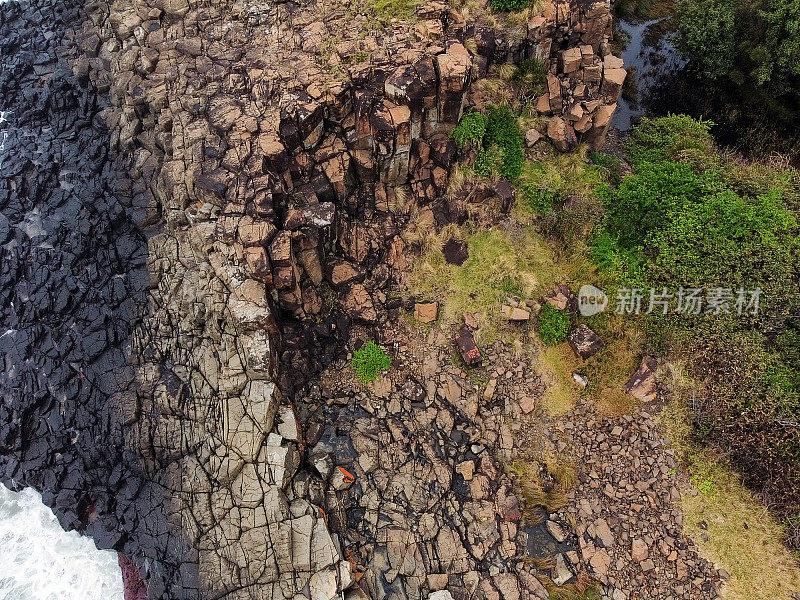 海浪在玄武岩火山柱上破裂的鸟瞰图，背景与复制空间