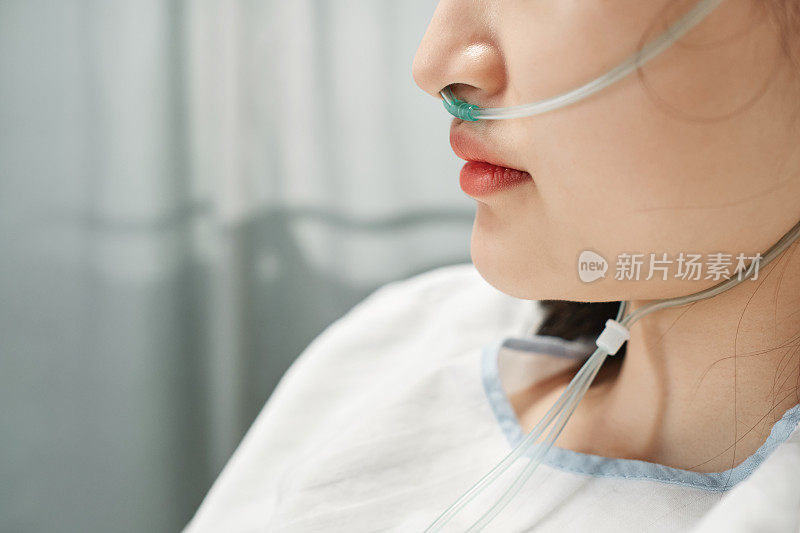 近距离侧面拍摄的年轻亚洲妇女戴鼻套管呼吸帮助在急诊室