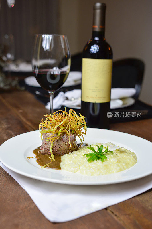 在豪华餐厅的桌子上放着用肉和香料调味的意大利烩饭，一瓶葡萄酒