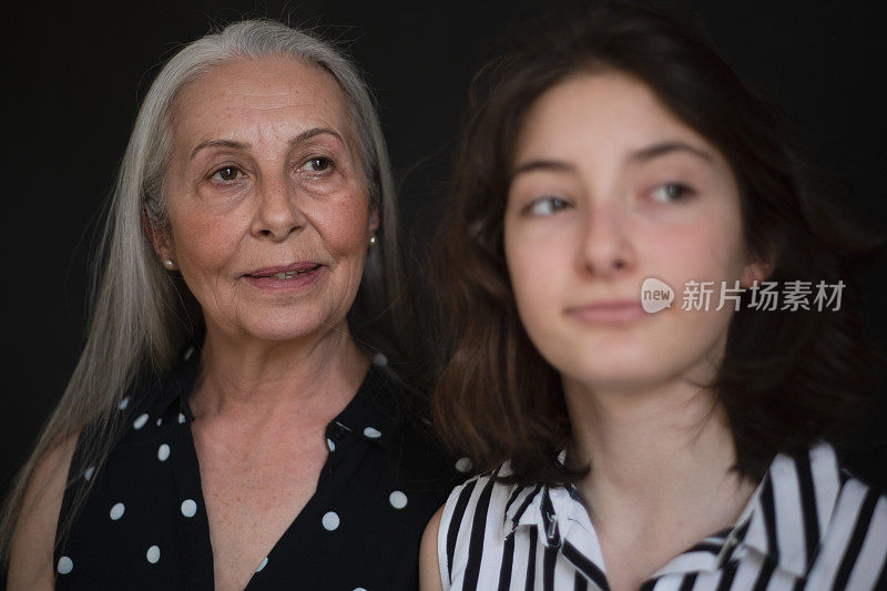 老祖母的肖像和她的孙女看着相机在黑色的黑土地