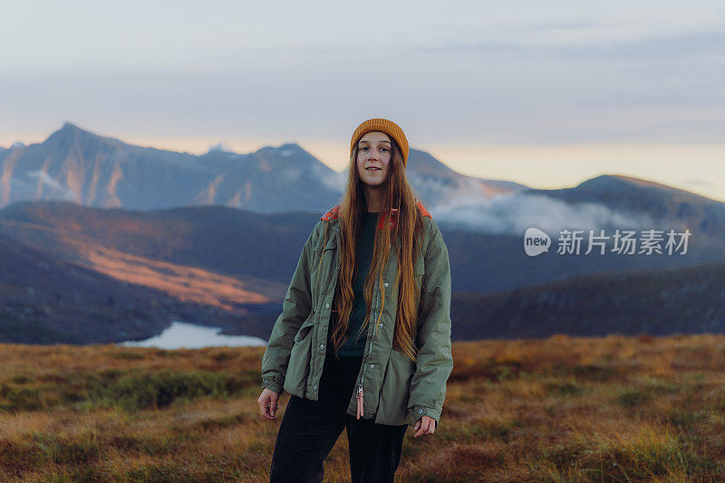 在挪威的山上，一个女人在眺望日落，徒步到云层之上的湖边