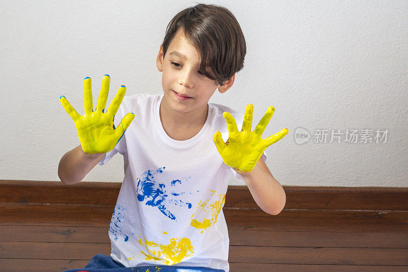 男孩在他的手上展示五颜六色的颜料