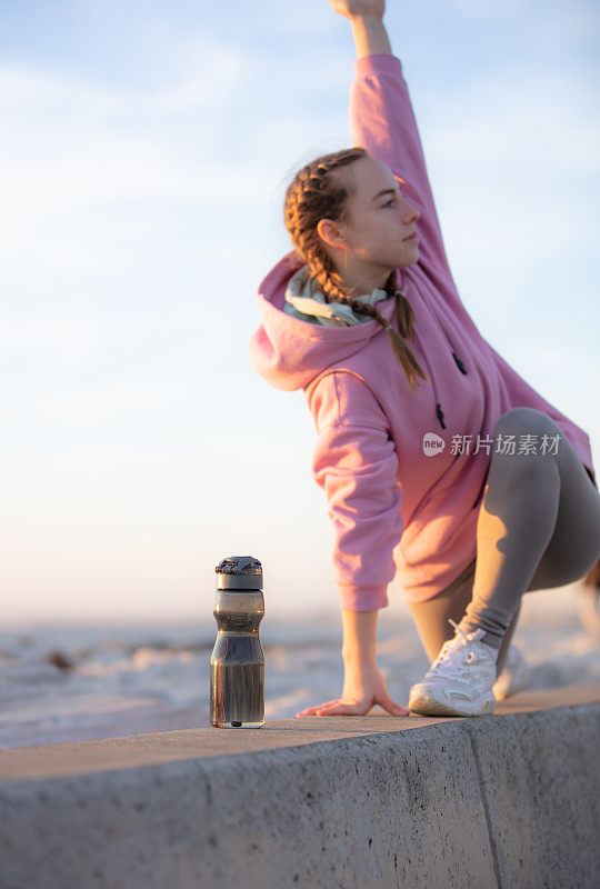 年轻女子正在海边户外锻炼时补水。