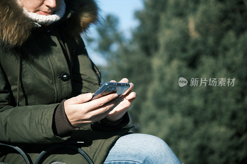 女子在冬季小镇使用智能手机
