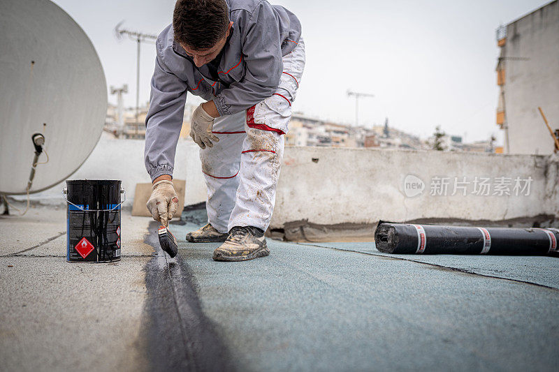 屋顶工人正在安装沥青防水膜卷，用于露台的防水