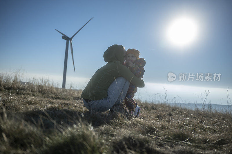 妈妈和孩子在山上的风能公园远足。