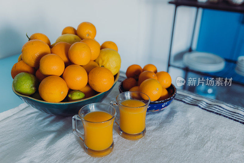 亮蓝色的厨房里有一盘色彩鲜艳的柑橘类水果和几杯新鲜的果汁
