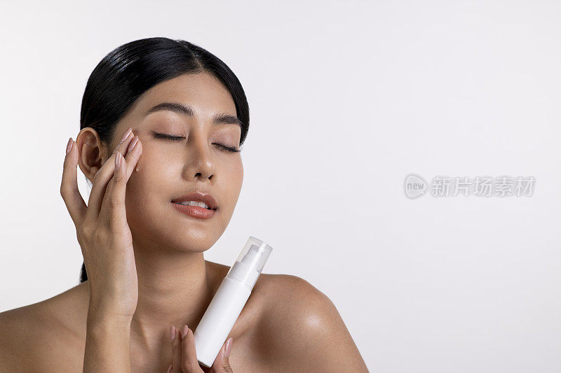 迷人的年轻亚洲女性正在脸上涂抹保湿霜