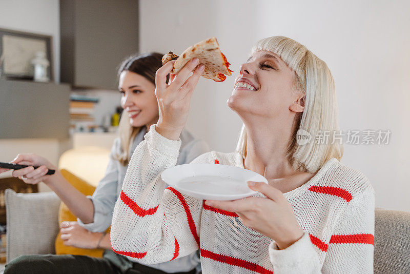 年轻女人在家里闲逛，享受披萨