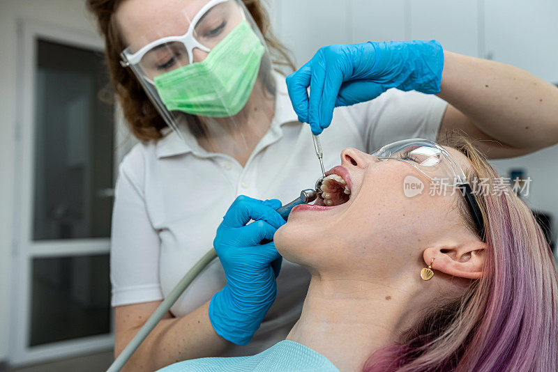 在一家牙科诊所里，一位女牙医正在给她矫正牙齿，一位女士坐在医疗椅上。