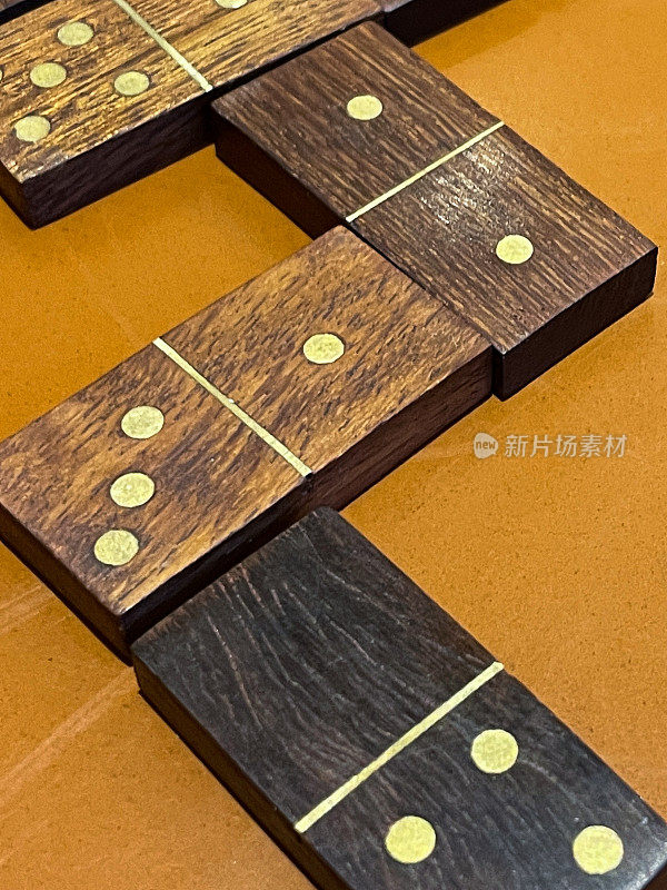 图像的木制多米诺骨牌游戏在橙色的桌子，匹配数字和曲折路径在著名的，流行的棋盘游戏，抬高视图
