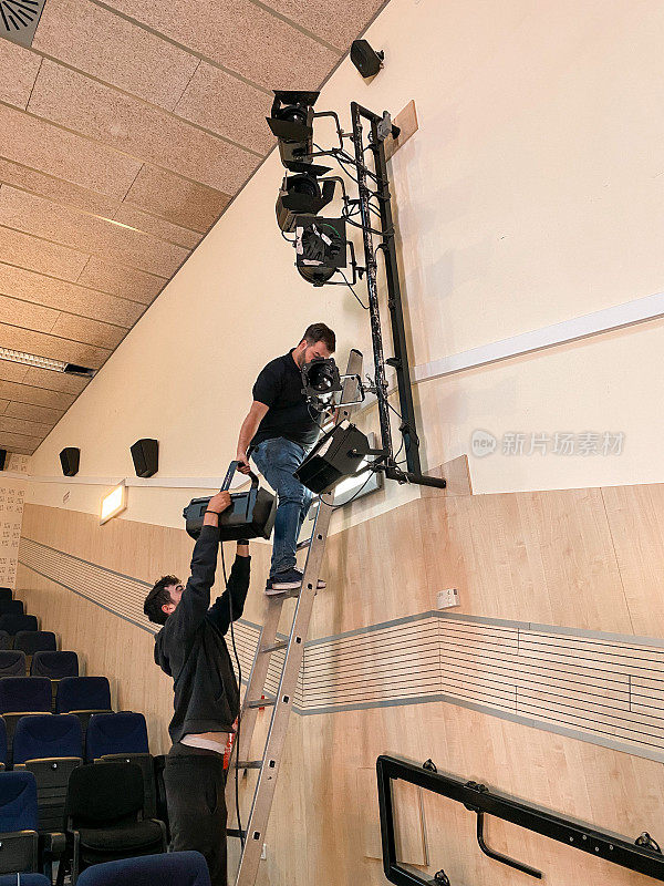 音响技师在梯子上为音乐表演安装射灯