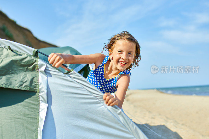 一个快乐的小女孩望着海边的帐篷外
