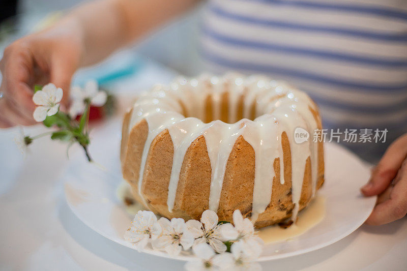 年轻女子用白花装饰kugelhopf蛋糕