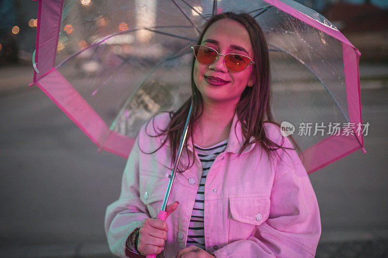 一个戴着太阳镜的女人在雨夜撑着伞散步的肖像