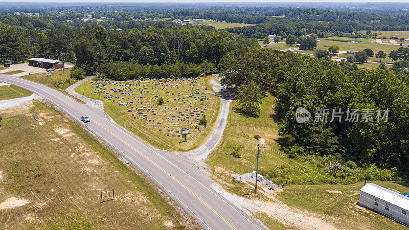 亚拉巴马州艾迪森市一条乡间小路旁的小墓地，墓碑上装饰着纪念阵亡将士纪念日的装饰。无人机航拍图。