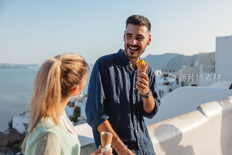 一对年轻的白人夫妇在圣托里尼岛享受约会，吃着冰淇淋