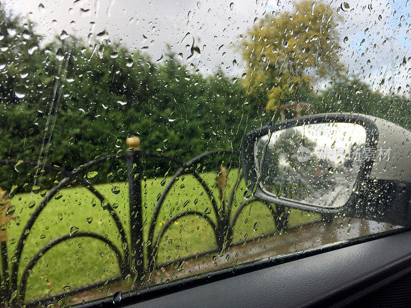 雨天的车窗和后视镜，以自然为背景。下雨天开车