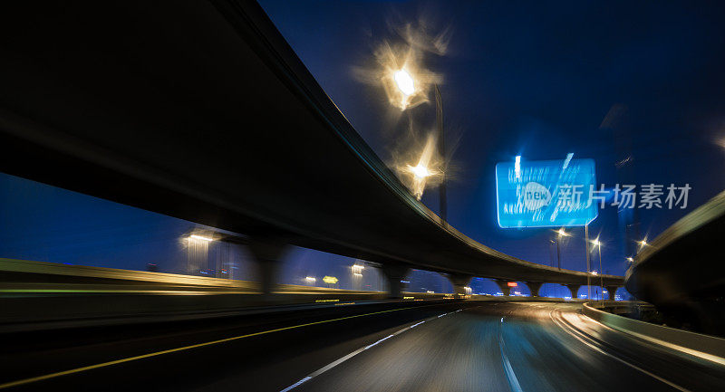 夜晚的高速公路在模糊的灯光下。佛罗里达州坦帕市被雨水浸透的道路上的照明立交桥道路。飓风后的软焦点，模糊的运动