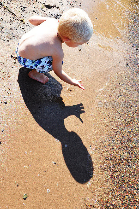 小男孩被他在海滩上神奇的影子迷住了