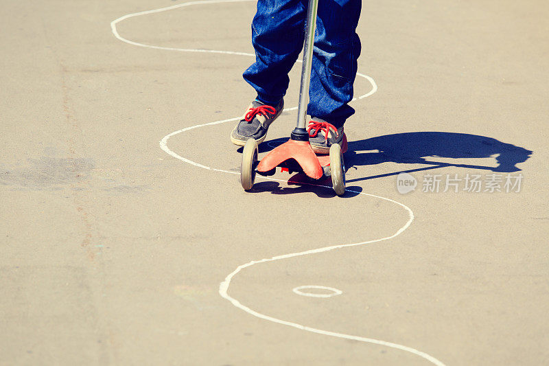 小男孩骑着滑板车在城市里