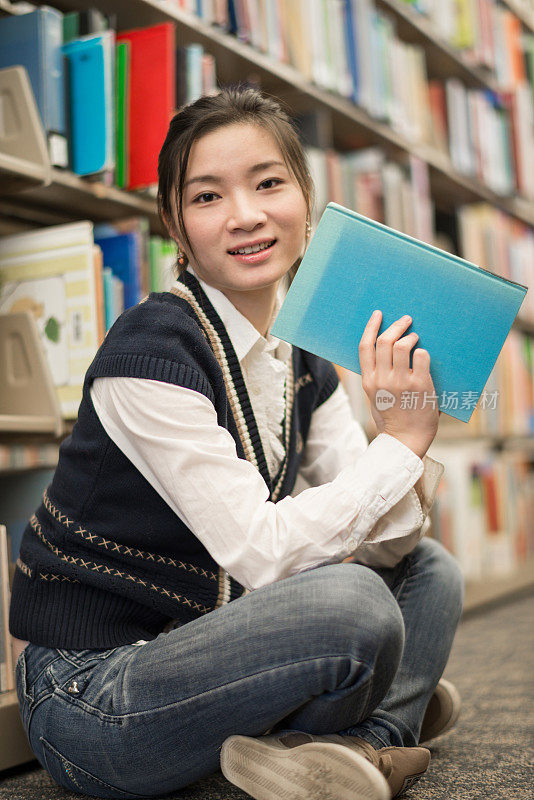一个女人拿着一本书靠近书架