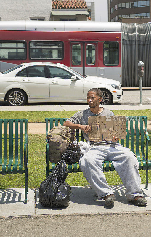 一个无家可归的人举着劳动节的标语