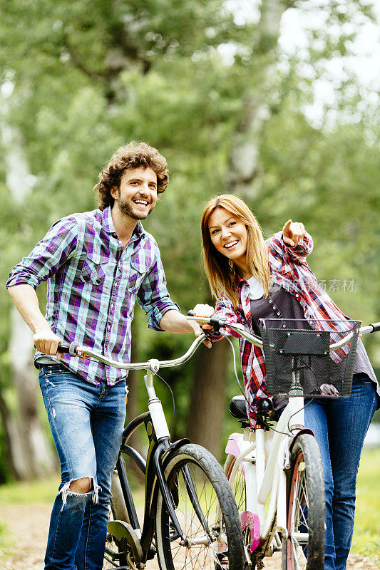 一对快乐的夫妇，推着自行车，走着。