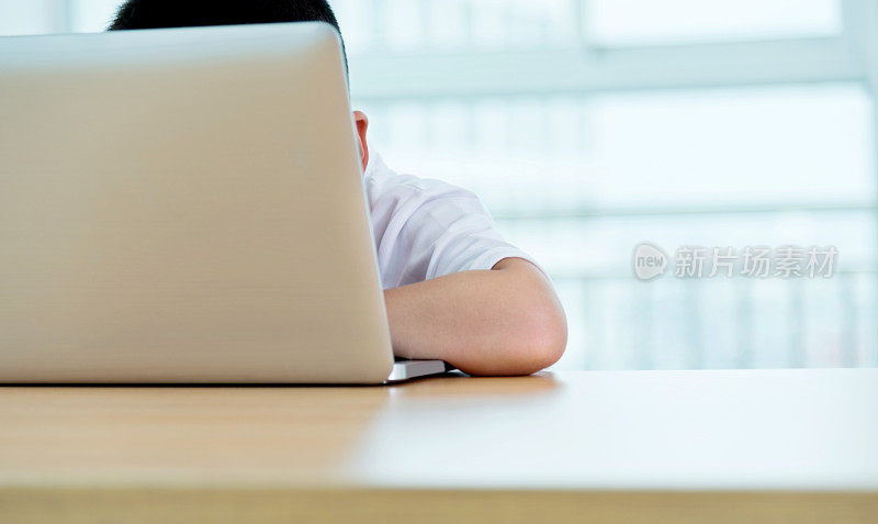 年轻的亚洲男孩在室内用笔记本电脑