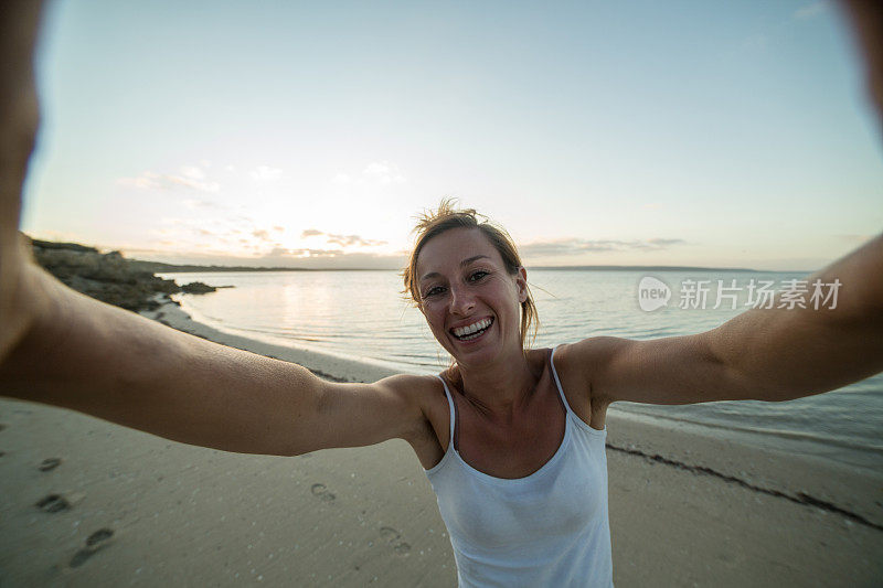 一名女子在日落时分的海滩上自拍