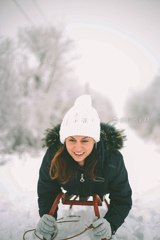 快乐的年轻女子在一个快速的雪橇骑下冰冷的斜坡