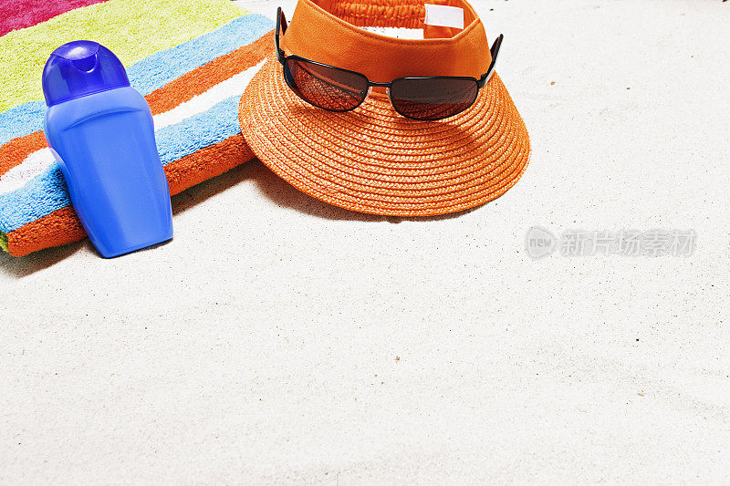 沙滩上有毛巾，太阳镜，防晒霜，帽子和复印空间