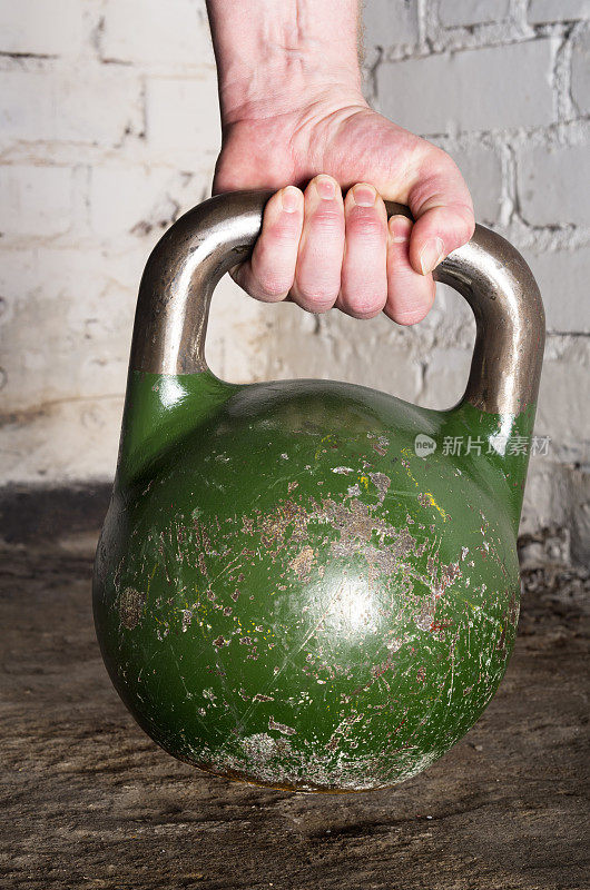 手拿一个绿色的24公斤壶铃