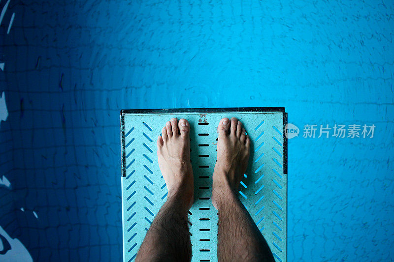 双脚踩在跳水板上越过泳池