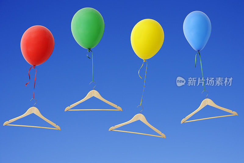 五颜六色的气球和衣架在晴朗的天空中升起