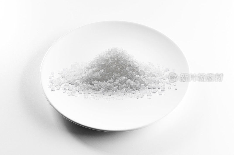 糖或盐堆在白色盘子上，隔离