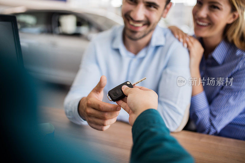 微笑的夫妇接受新汽车钥匙的特写。